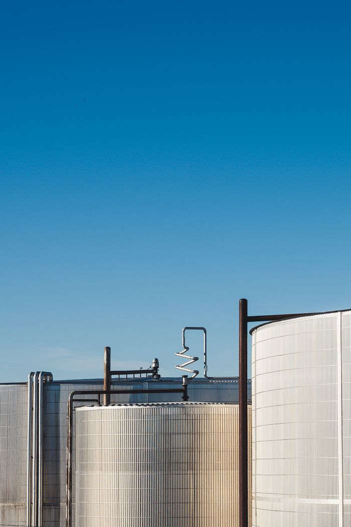 The Role of Chemical Trading Companies in Global Supply Chains Minimalist photo of large industrial tanks under clear blue sky.